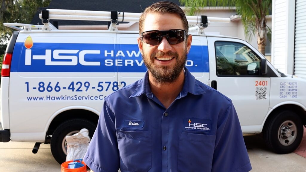 HSC employee in uniform smiling for picture while standing in front of service van