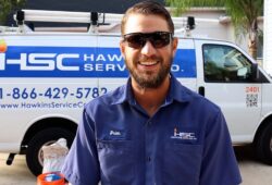 HSC employee in uniform smiling for picture while standing in front of service van