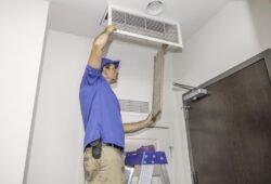 Technician on a ladder replacing a dirty air filter
