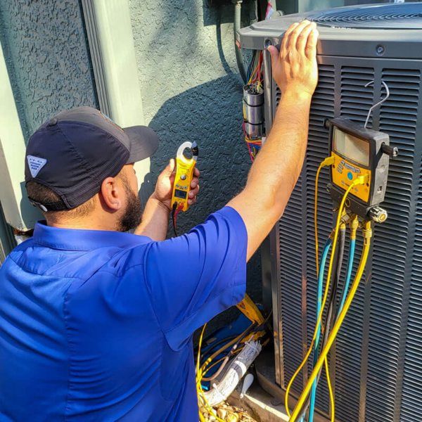 A Hawkins Service Company technician inspecting an outdoor HVAC unit.