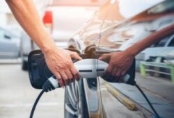 Hand hold of charging modern electric car battery on the street which are the future of the Automobile, Close up of power supply plugged into an electric car being charged for hybrid . New era of vehicle fuel.