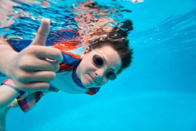 kid showing thumps up in the pool