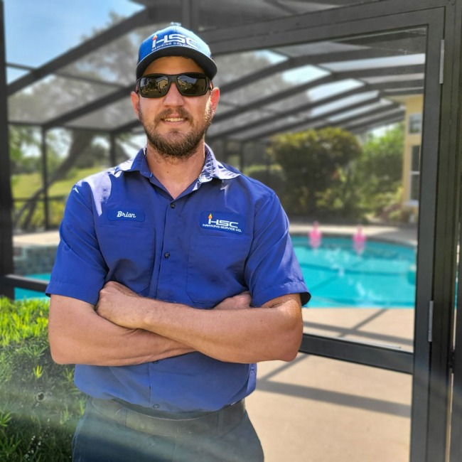 Hawkins Service Company pool technician posing in front of a pool with a screened in patio
