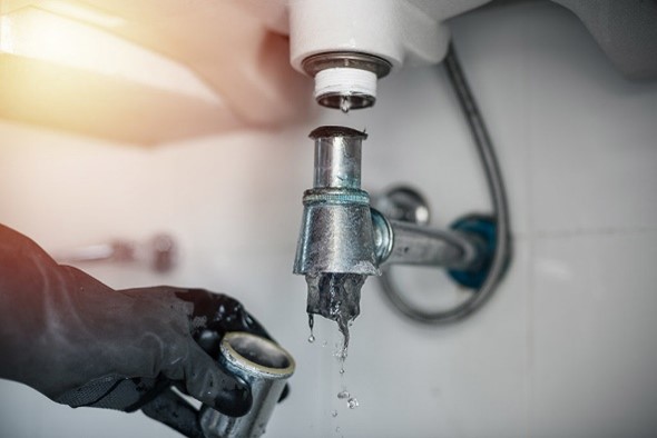 Plumber fixing pipe connection under bathroom sink