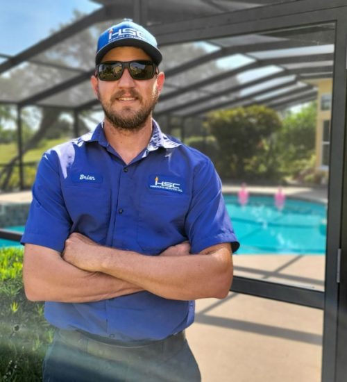Hawkins Service Company pool technician posing in front of a pool with a screened in patio