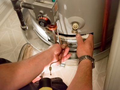 A man uses a flashlight to help him see the water heater in a dark closet